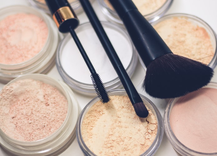 Traditional makeup - pressed powders - are laid out with some makeup brushes.