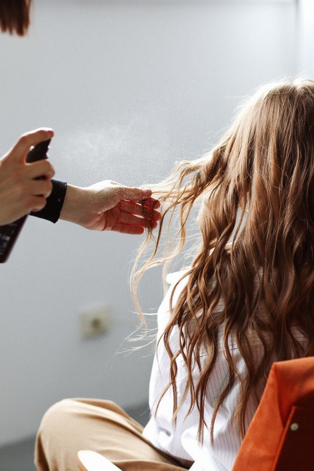 Spraying hair to prevent frizz.